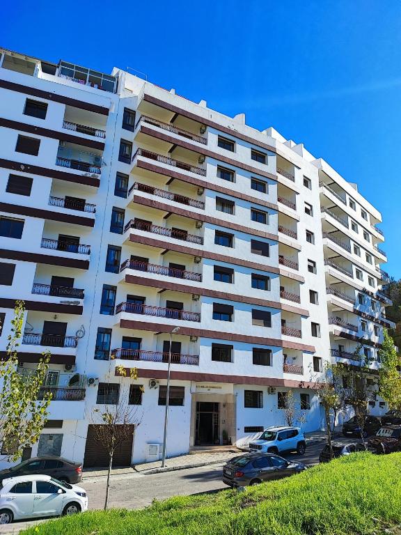 a large white building with cars parked in a parking lot at les Belles Sejours in Tangier