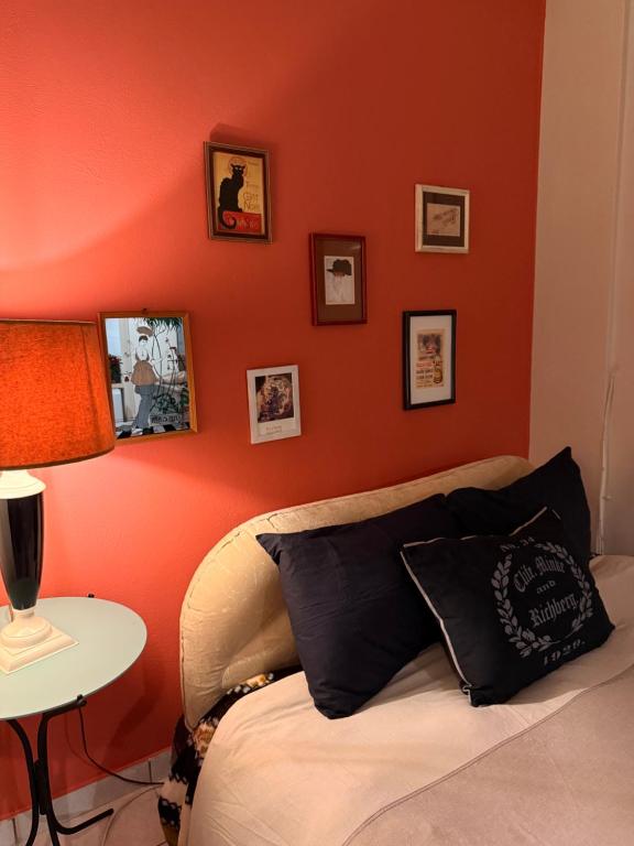 a bedroom with an orange wall with a bed and a table at Boho ElTha Lotus in Patra