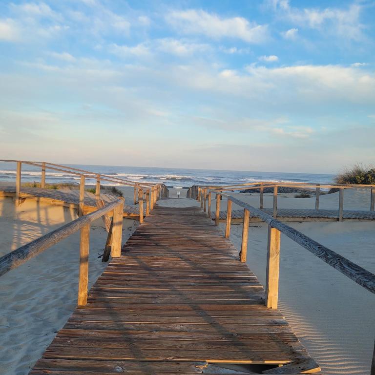 a wooden boardwalk stretches out into the water on the beach at Beachfront apartment T2 Costa Nova Surf Aveiro in Gafanha da Encarnação