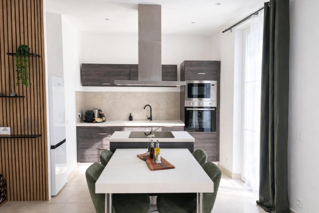 a kitchen with a white table and a sink at Apparemment cosy avec balcon plein centre de Cannes - Carla home in Cannes