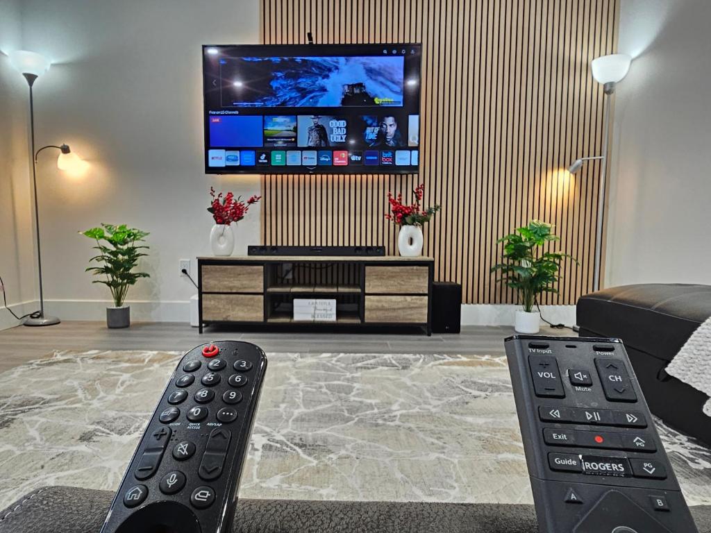 ein Wohnzimmer mit zwei Fernbedienungen und einem Fernseher in der Unterkunft Elegant 3-bedroom Home Away From Home, Luxury Styled in St. John's