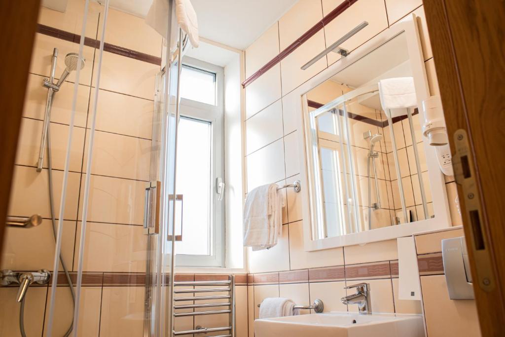 a bathroom with a shower and a sink and a mirror at Hotel Sliško in Zagreb