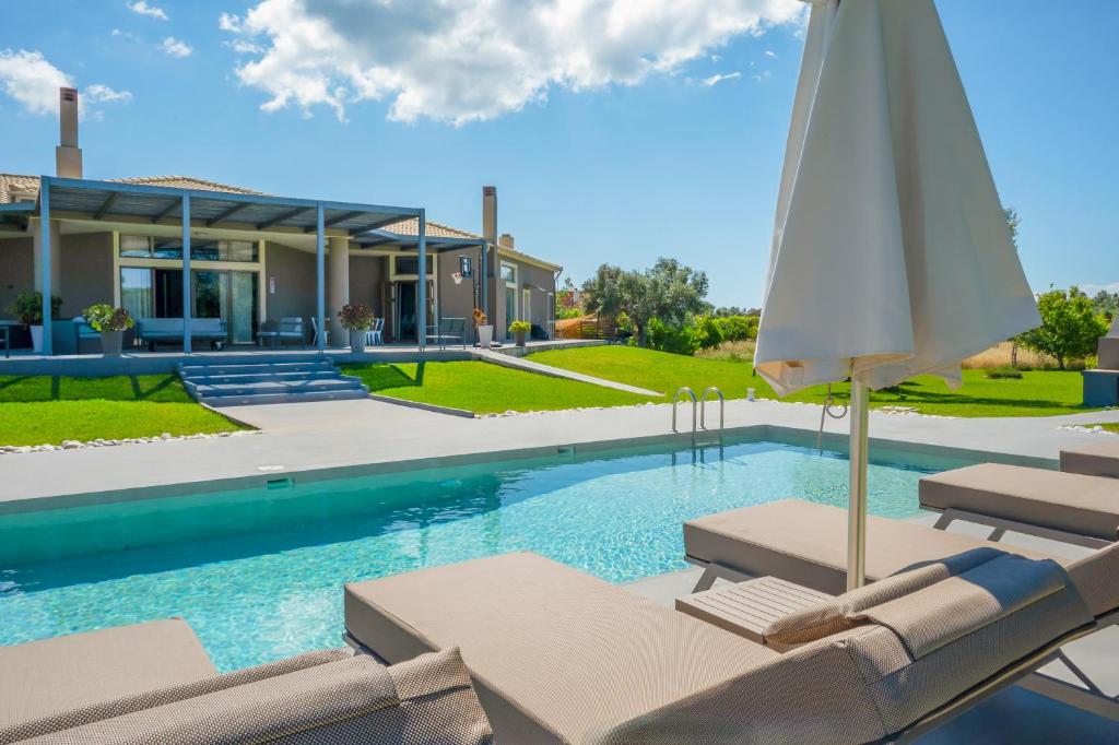 a pool with lounge chairs and an umbrella in front of a house at Villa Katrin in Svoronata