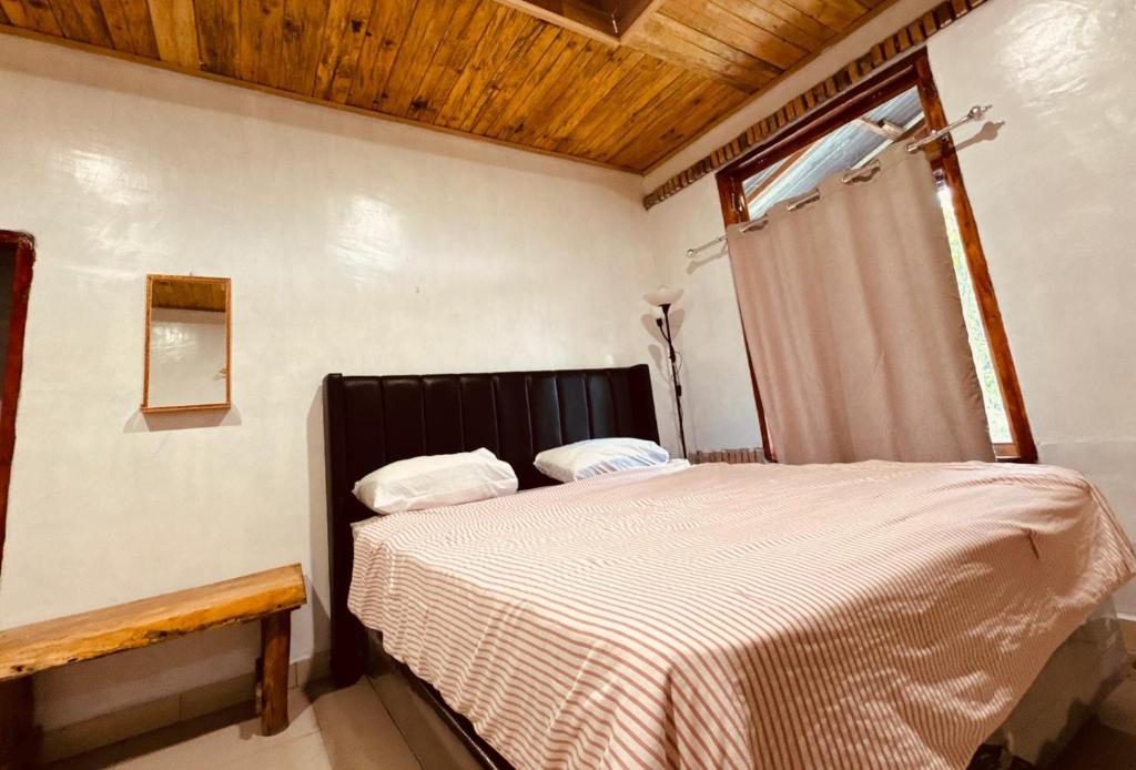 a bed in a bedroom with a wooden ceiling at Hot Chilli Hotel in Tuktuk Siadong