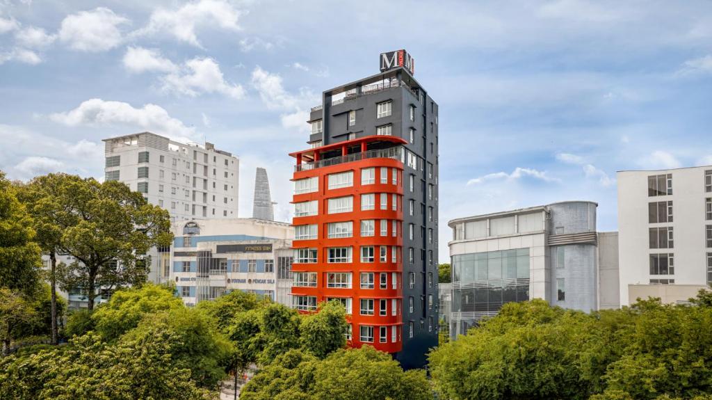 a tall red building in the middle of a city at M Village Hotel Nguyễn Du, a brand of Modern Village Lifestyle in Ho Chi Minh City