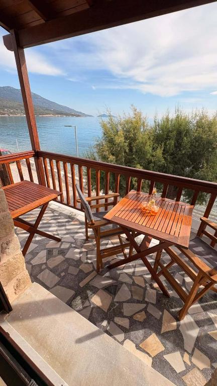 a wooden table and chairs on a balcony with the water at Kỳma - Stone Luxury Villa in Órmos Koumaíïkon