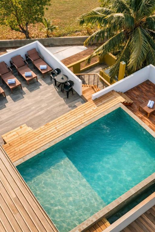 an infinity pool with chairs and a table and a swimming pool at Cozy Roots Fuvahmulah in Fuvahmulah