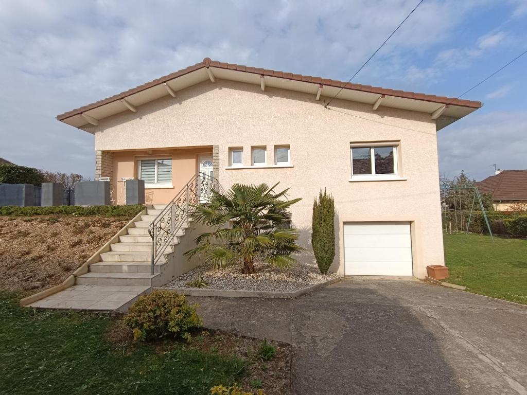 a house with a garage and a palm tree in front of it at Maison grande terrasse Poligny in Poligny