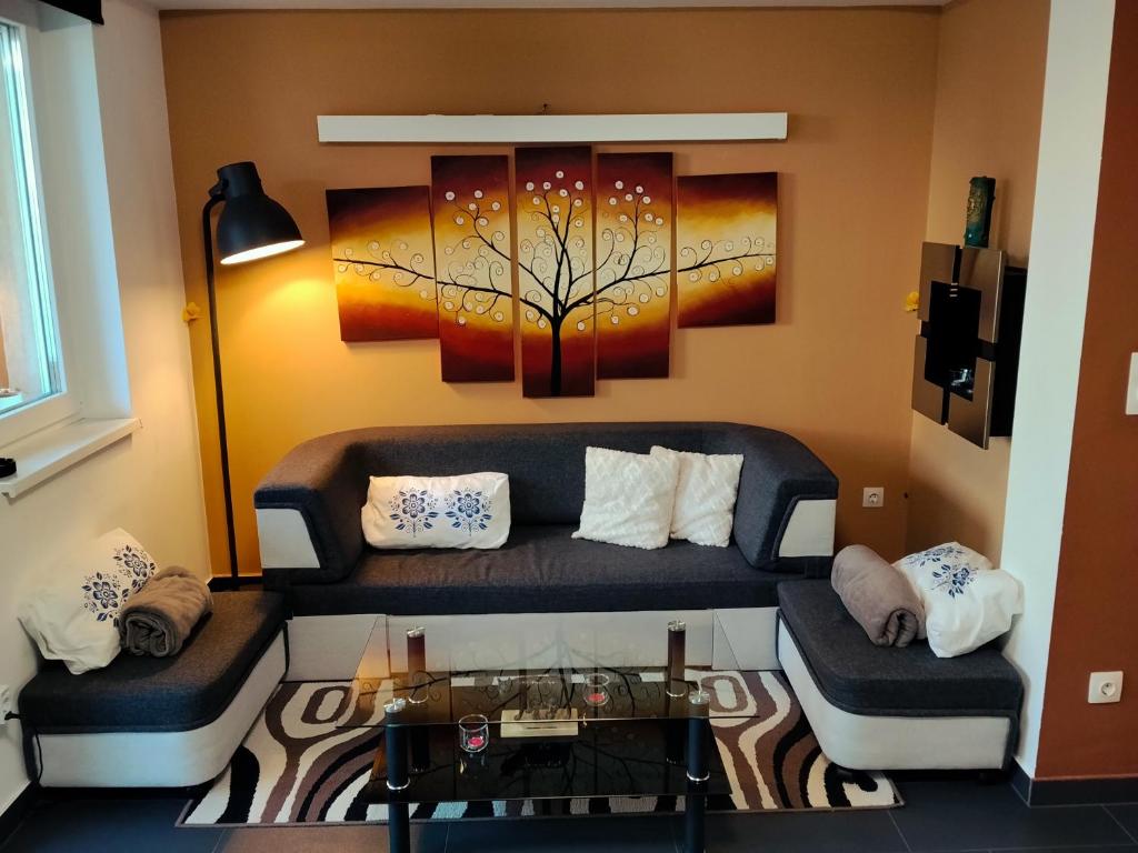 a living room with a couch and a tree painting at Italia House in Fót