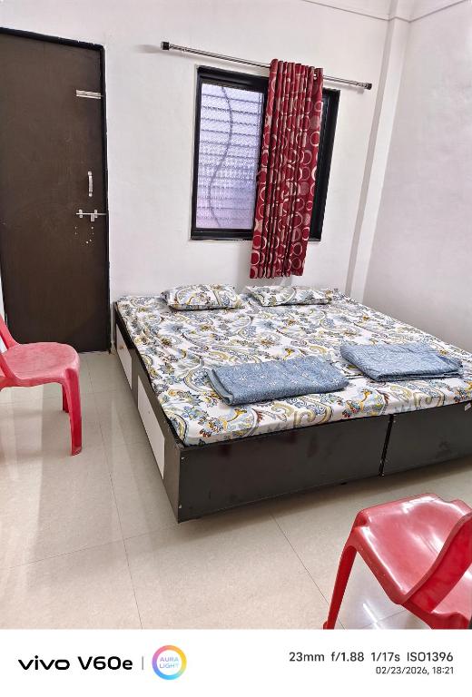 a bedroom with a bed and a red chair at Durga Bhakt Niwas in Tuljapur