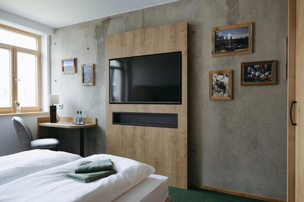 a bedroom with a bed and a flat screen tv at Grünbauer - Der Landgasthof in Reuth bei Erbendorf