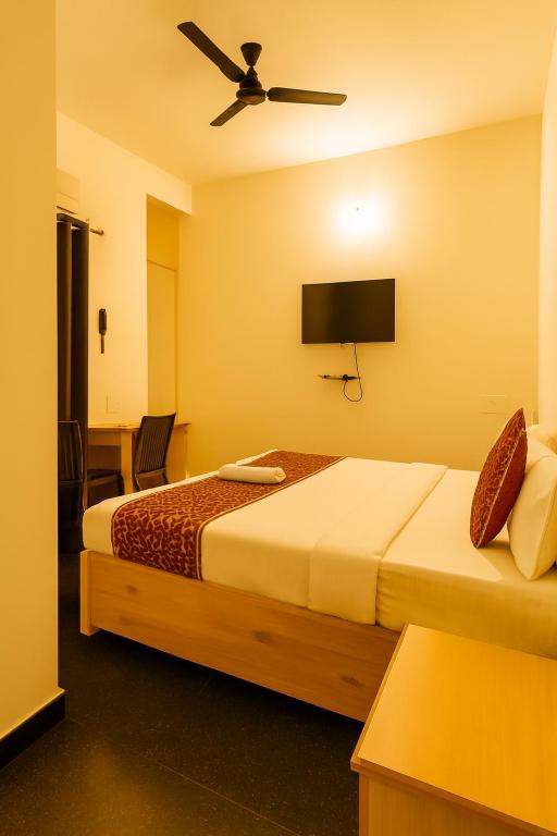 a hotel room with two beds and a flat screen tv at Mysore Couple Friendly at 999 in Mysore