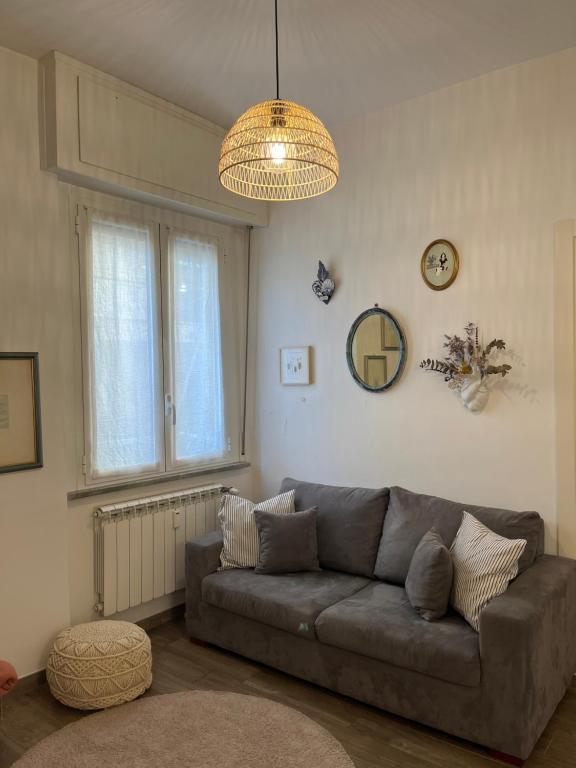 a living room with a gray couch and a chandelier at Casa Angiolina in Chiavari