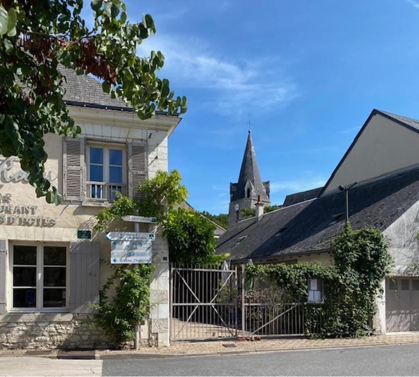 a building with a gate in front of a church at Le clos aux roses in Chédigny