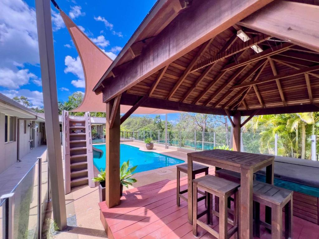 a wooden table and chairs on a patio with a pool at Solis Acreage Escape in Advancetown