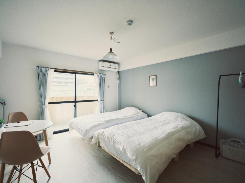 a bedroom with two beds and a table and a window at vetta kumamoto suizenji2 308 in Kumamoto