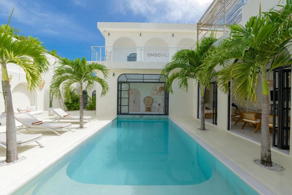 a pool with palm trees in front of a building at 5BR Ocen View Villa in Jimbaran in Jimbaran