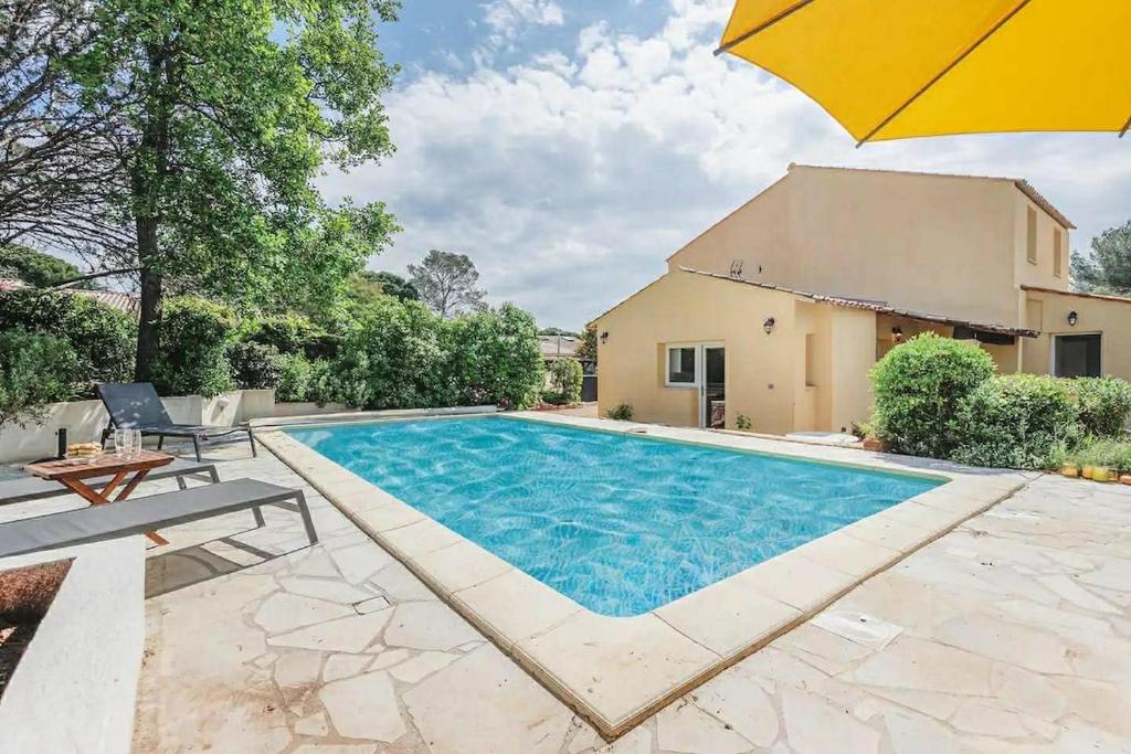 a swimming pool with an umbrella next to a house at Les cinq soleils in Roquebrune-sur-Argens
