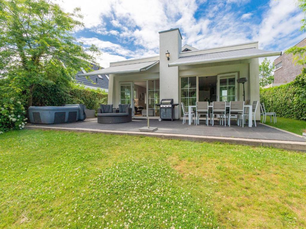 a house with a patio with chairs and a lawn at Scandinavisch Nr. 221 | 8 Pers. Jacuzzi in Zeewolde