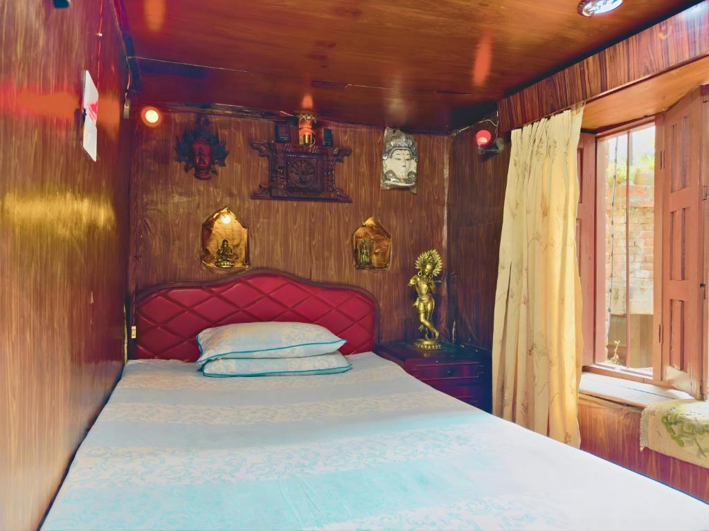 a bed with a red head board in a room at Newa Home Bhaktapur in Bhaktapur