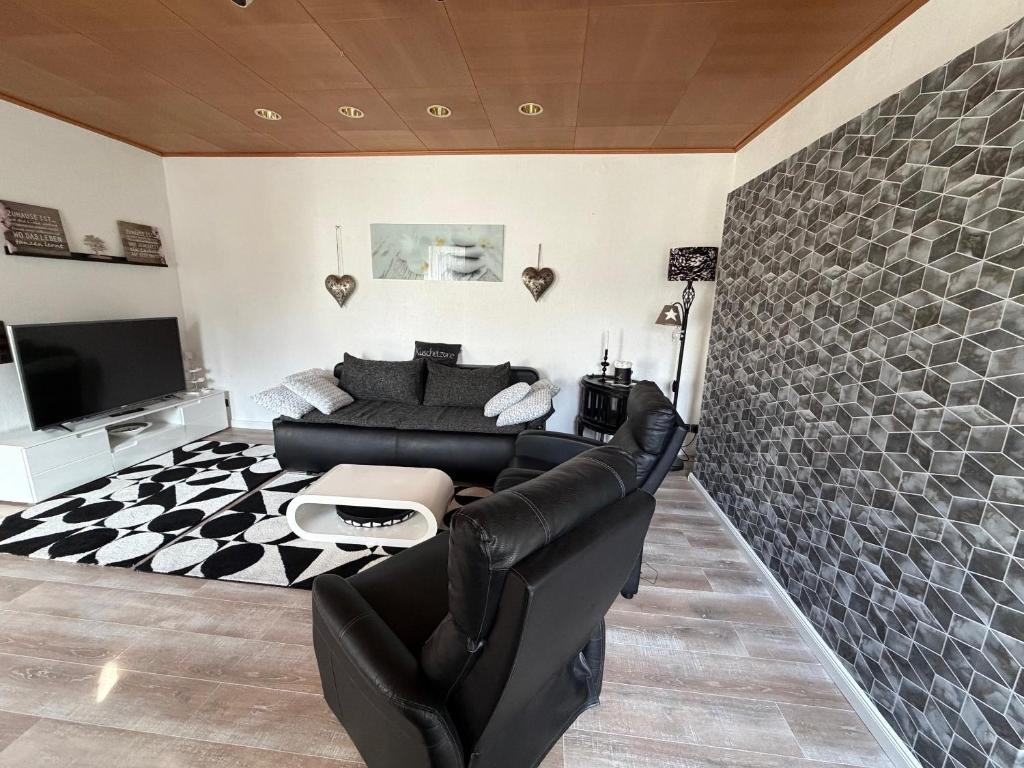 a living room with a black leather couch and a tv at Sterntaler Melsungen in Melsungen