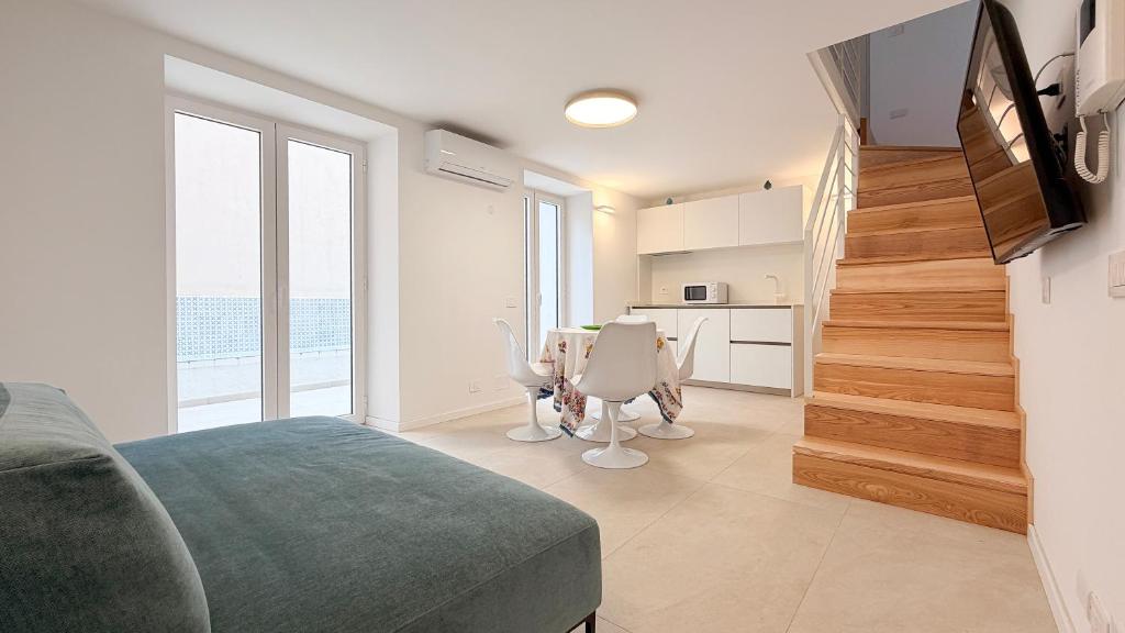 a bedroom with a staircase and a living room with a table at Cefalù Beach Garden House in Cefalù