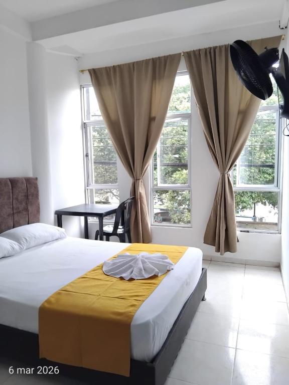 a bedroom with a bed and a table and windows at Hotel SR, Villa Garzón in Villagarzón