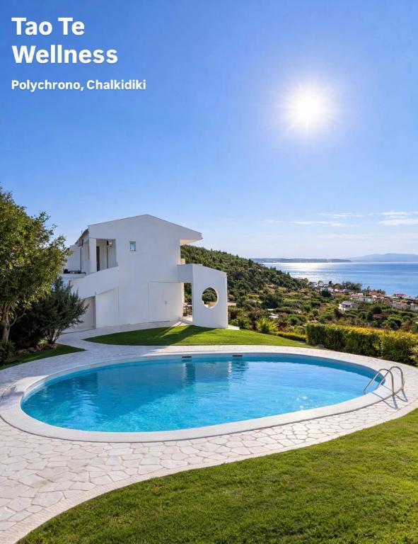 a villa with a swimming pool in front of a house at Tao Te Wellness in Polychrono