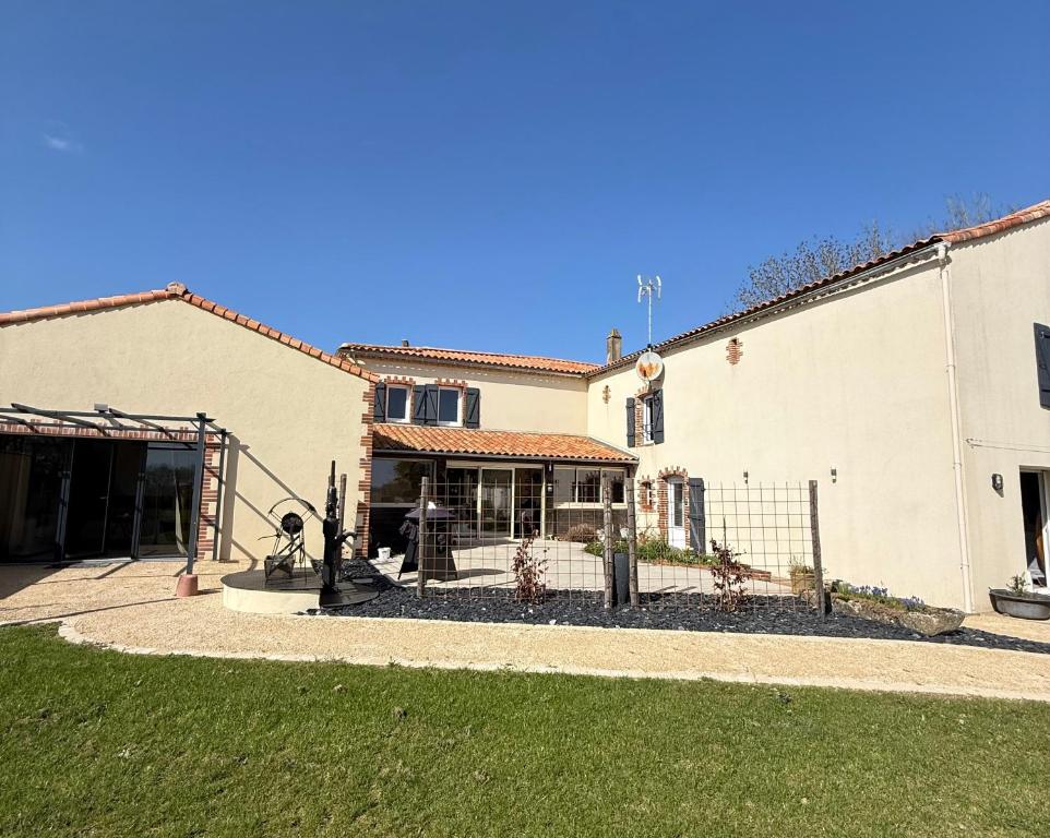 a building with a fence in front of a yard at Chambre d´hôtes La Jonchère in Les Herbiers