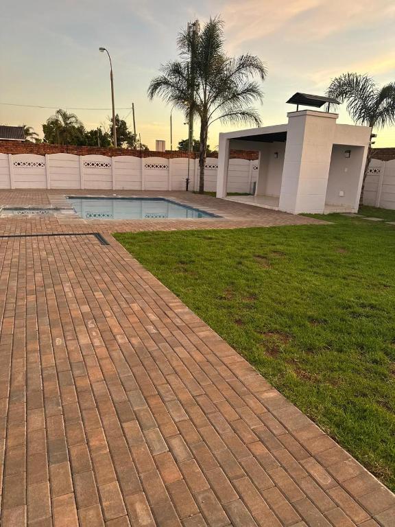 a brick walkway in front of a building with a pool at Phela Guesthouse in Edenvale