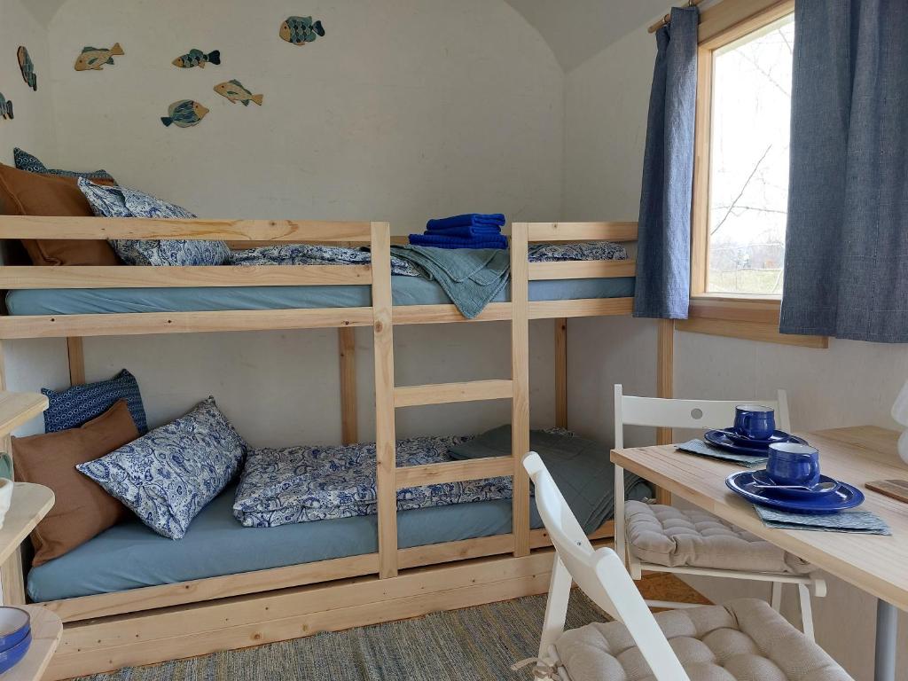 a room with bunk beds and a table and a desk at Schäferwagen Gartenblick Nr 4 in Radebeul