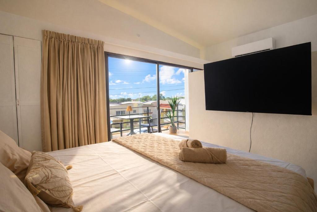 a bedroom with a large bed with a flat screen tv at Loveli Stay Aruba in Oranjestad