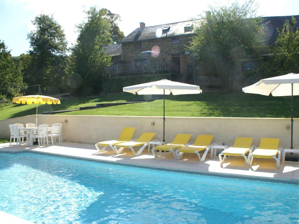 a swimming pool with chairs and umbrellas next to a swimming pool at Spacious holiday home in Sussac with pool in Châteauneuf-la-Forêt
