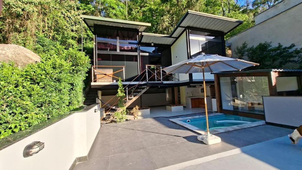 a house with a swimming pool and an umbrella at Loft com piscina, sauna e hidro in Niterói