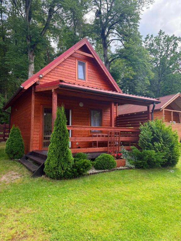 a log cabin with a porch in the grass at Chaty Mazur w Wierzbie in Ruciane-Nida