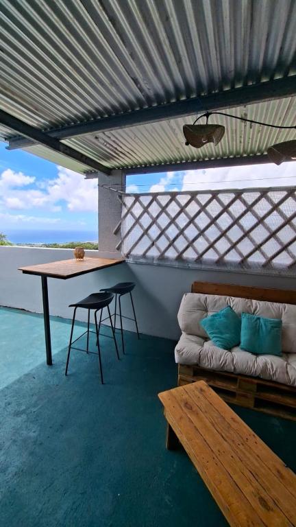 a room with a table and a bench on a roof at Le Tranqu'Île in Sainte-Marie