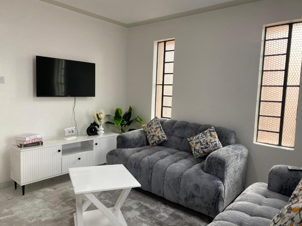 a living room with a couch and a tv at Modern staycation -ruaka in Ruaka