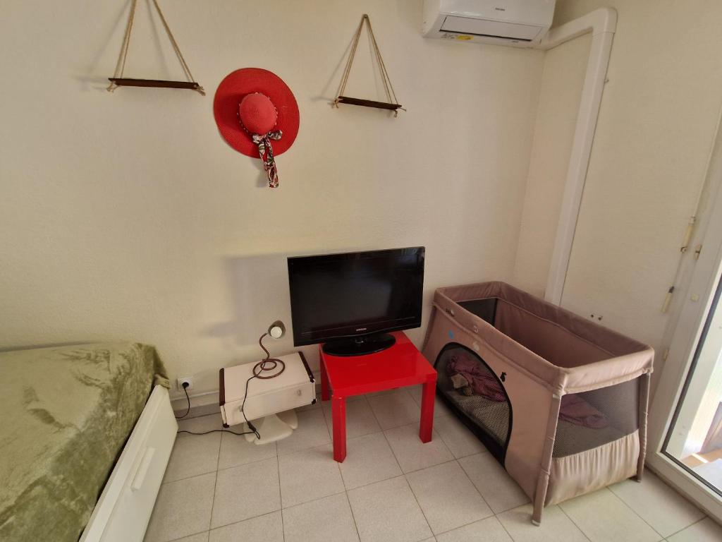 ein Schlafzimmer mit Fernseher, rotem Tisch und Bett in der Unterkunft Studio DOUILLET in Aix-en-Provence