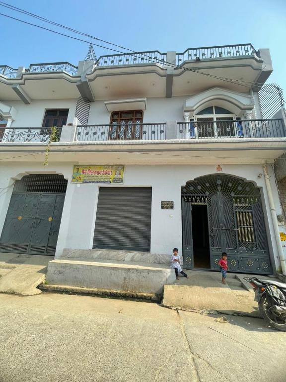 two children sitting in front of a house at Ravi Tomar Homestay in Phalauda