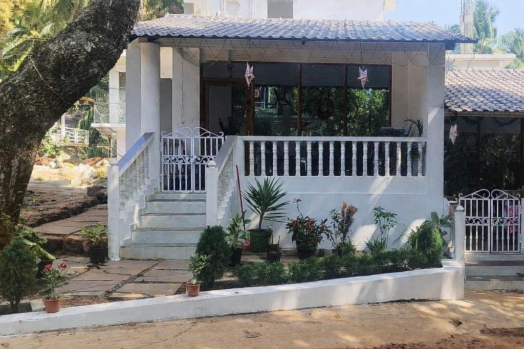 a house with a white fence and a porch at Anna Cottages Agonda in Agonda