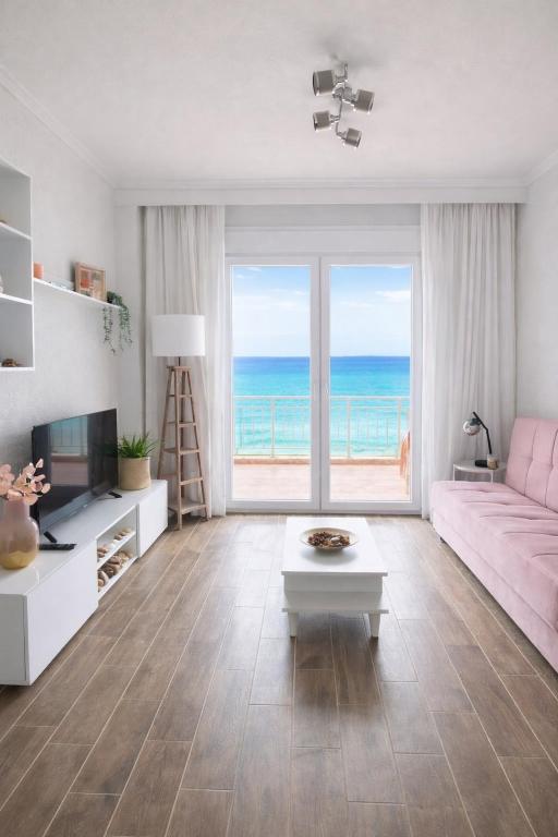 a living room with a pink couch and a view of the ocean at Ethereal Beach House in Hanioti