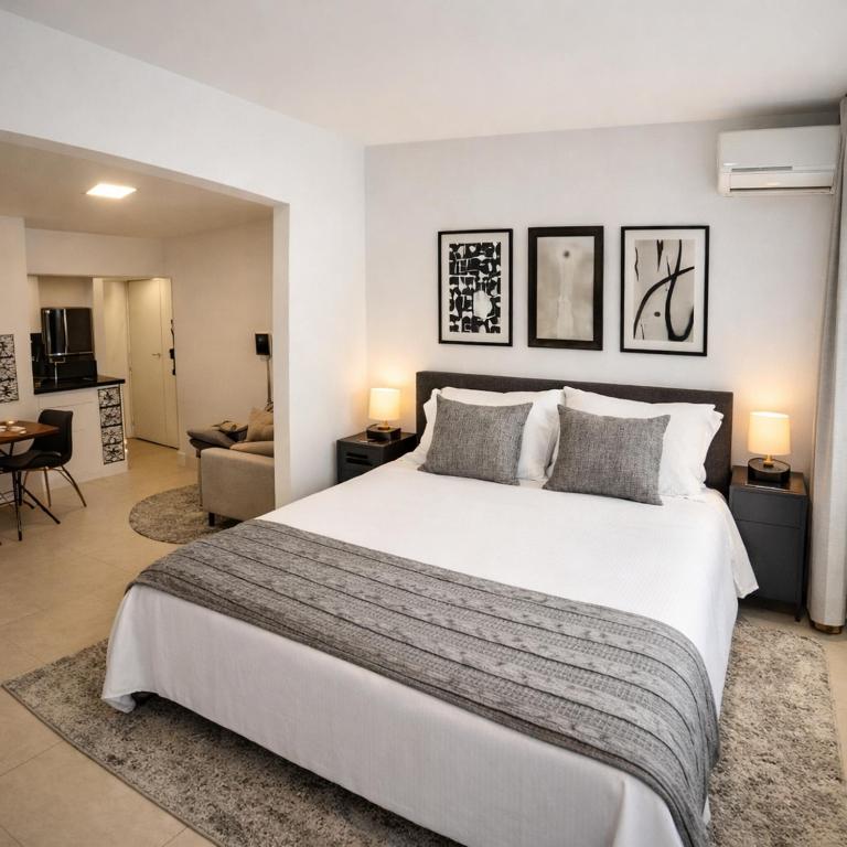 a bedroom with a large bed and a living room at Studio 929 Gold Star 400m Ferry to Rio 1Gb Wi-Fi in Niterói