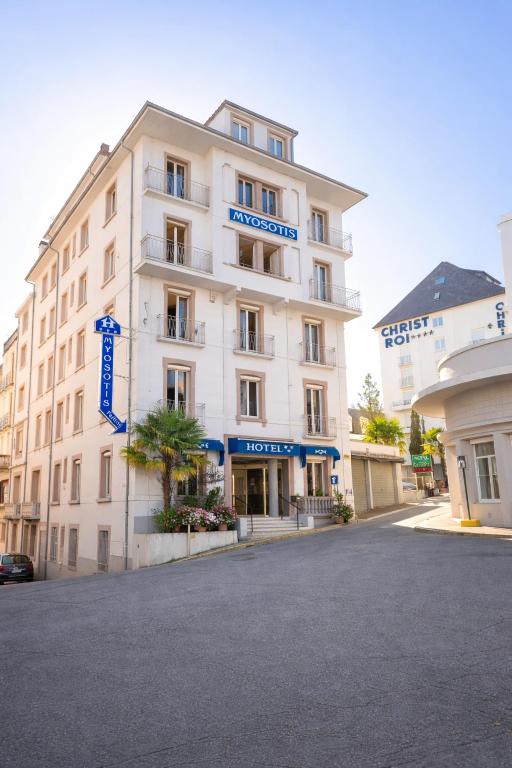 a large white building with a blue sign on it at Hôtel Myosotis in Lourdes