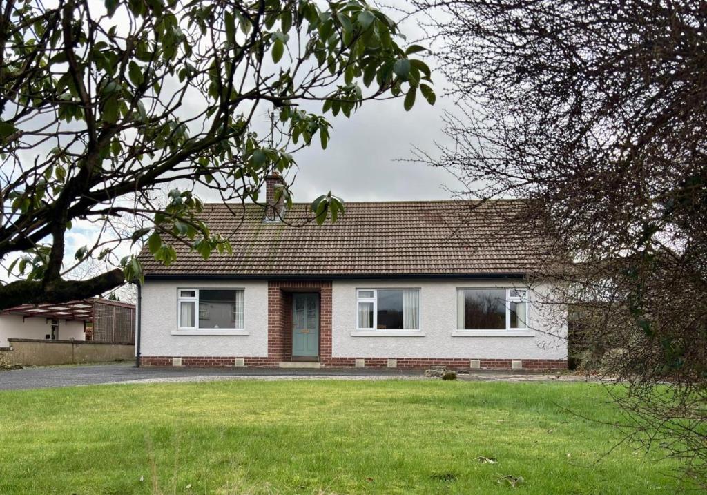 a house with a green lawn in front of it at Kinard in Lisbellaw