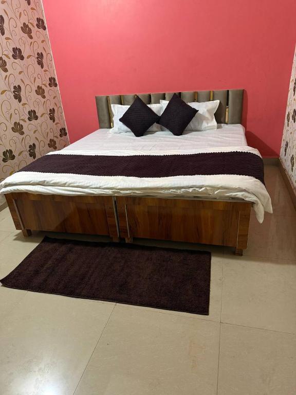 a bedroom with a wooden bed with black and white pillows at Karuna Homestay in Ujjain