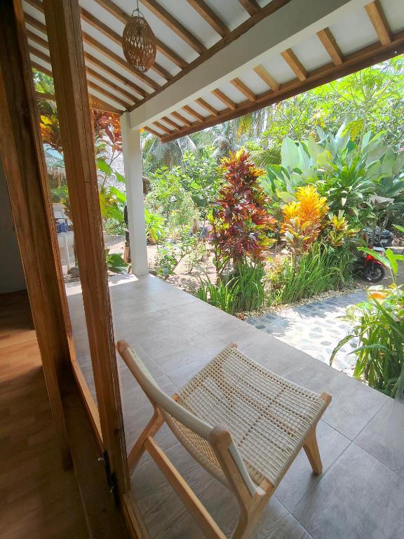 a chair on a porch with a view of a garden at anik homestay & dormy Batukaras in Batukaras
