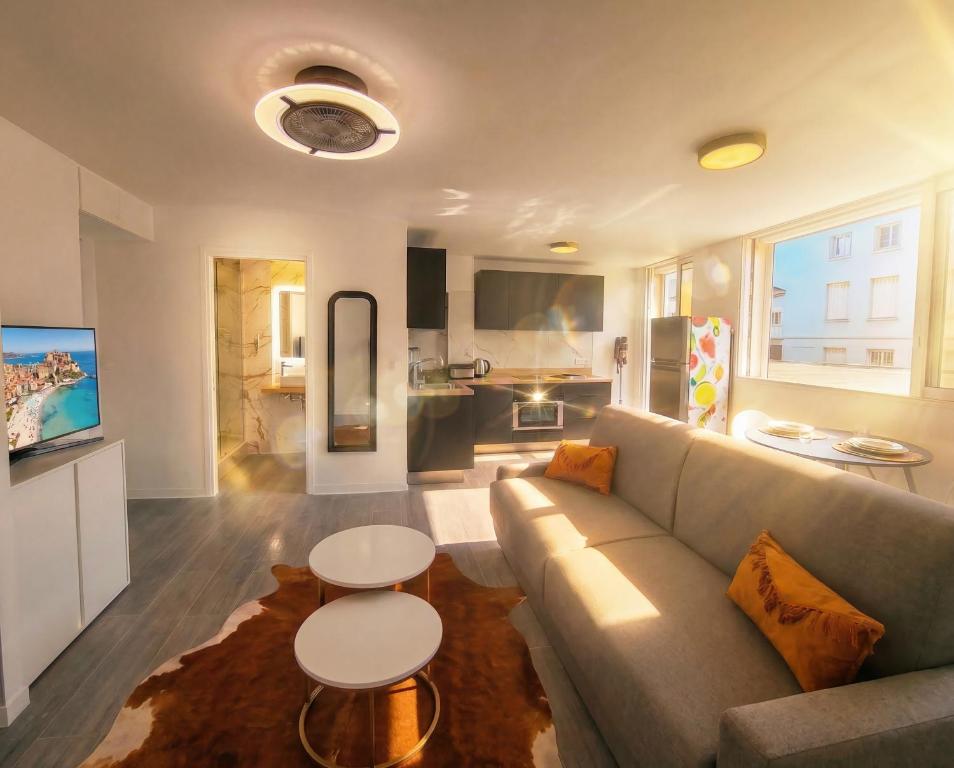 a living room with a couch and two tables at Studio Les Allées in LʼÎle-Rousse