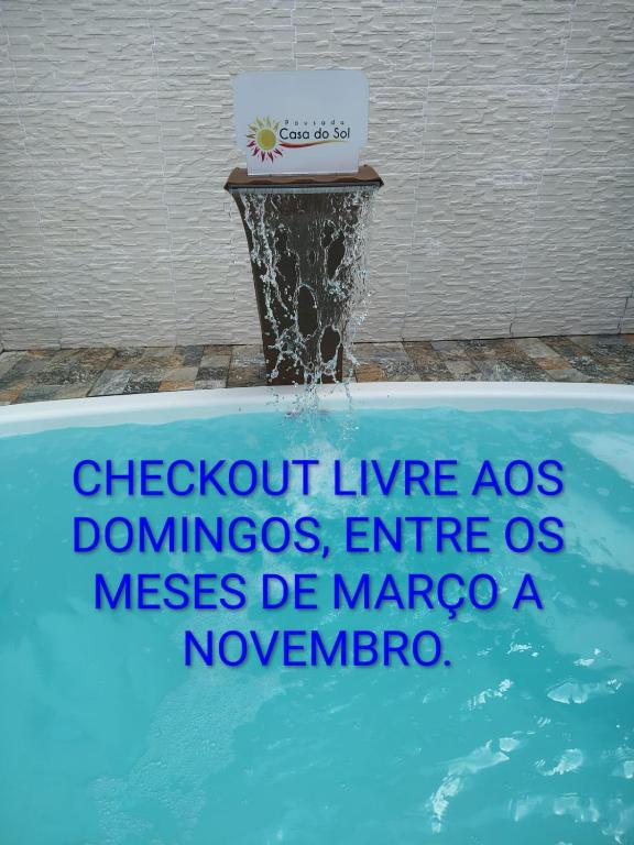 a water fountain in a swimming pool with a sign at Casa do Sol III in Peruíbe