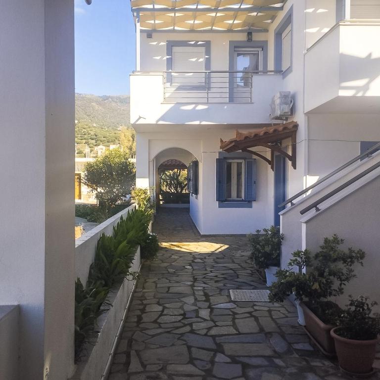 a hallway of a white building with a stone walkway at Kampos Bliss Studios in Votsalákia