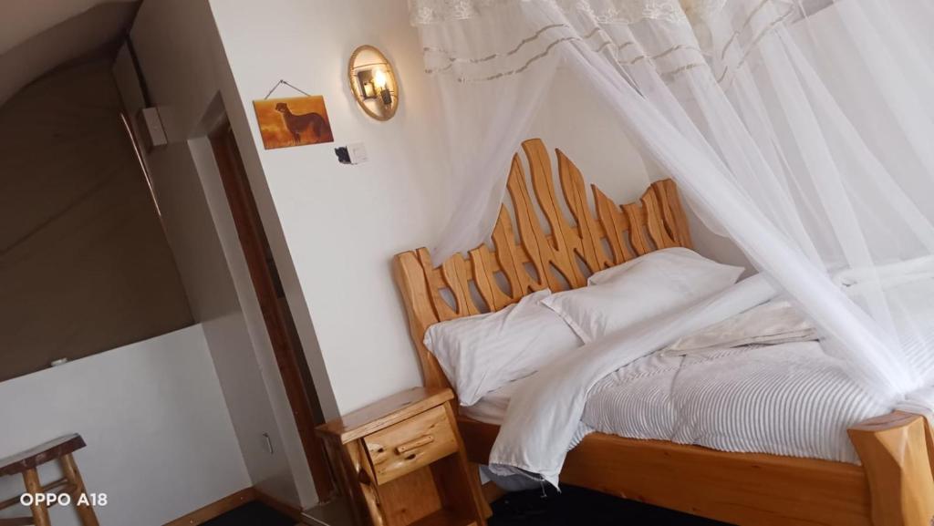 a bedroom with a canopy bed with white sheets at Hotel White Sandcastle Mara in Sekenani